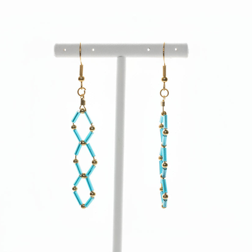 Pair of blue beaded earrings on a white stand against a white  background