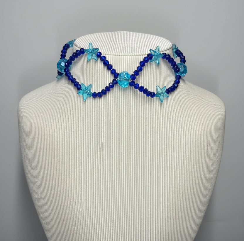 Blue beaded infinity necklace on a mannequin head against a gray background