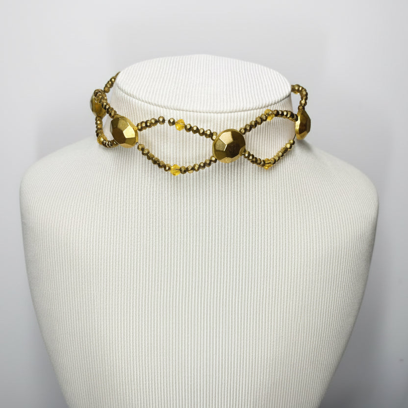 Gold necklace on a mannequin bust against a plain background