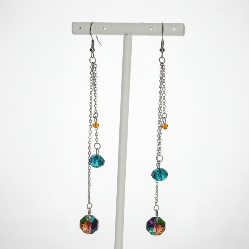 Pair of dangling earrings with colorful beads on a white stand against a white background