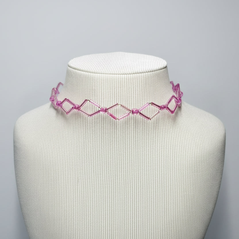 Pink geometric choker on a mannequin neck against a gray background