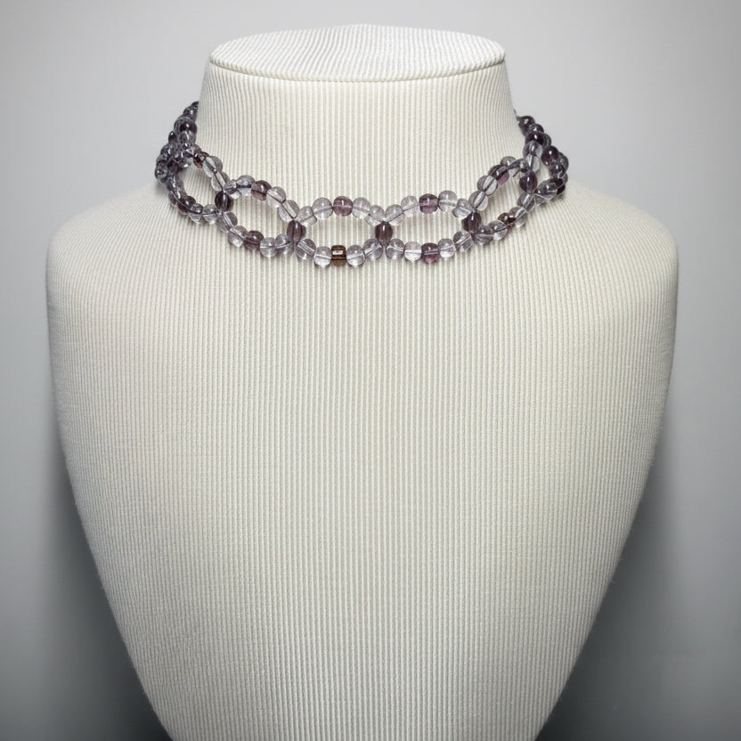 Necklace on a mannequin bust against a plain background