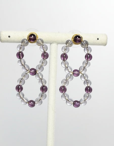 Beaded earrings on a white stand against a gray background