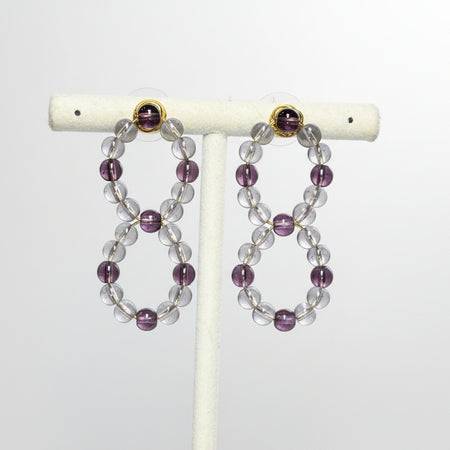 Beaded earrings on a white stand against a gray background