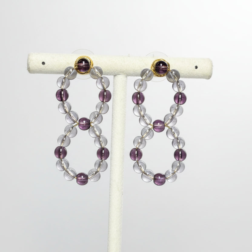 Beaded earrings on a white stand against a gray background