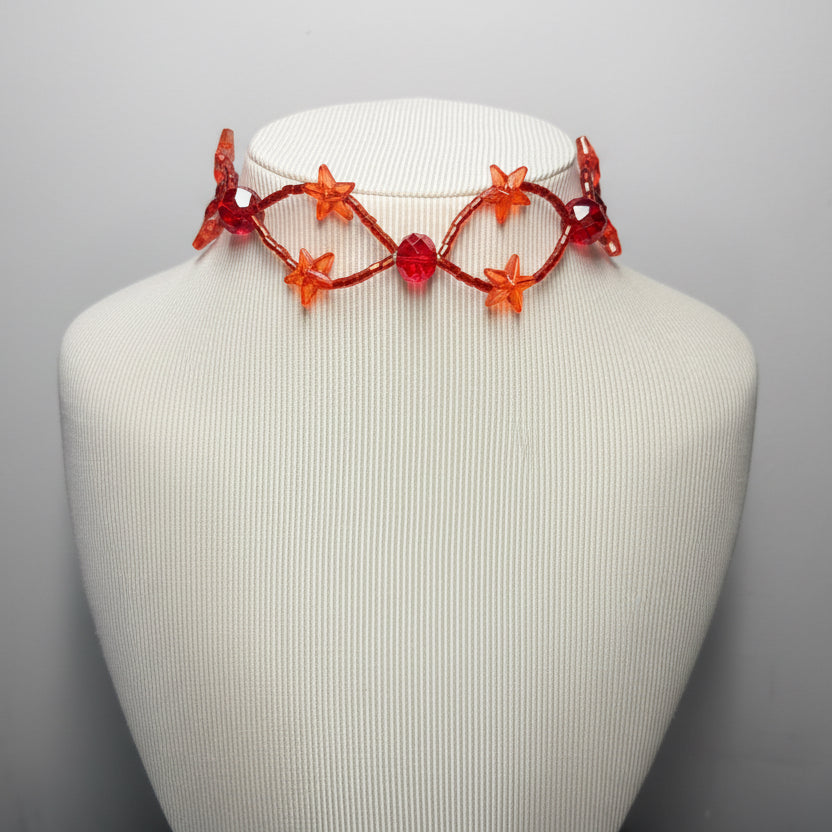 Necklace with red and orange beads on a mannequin bust against a gray background