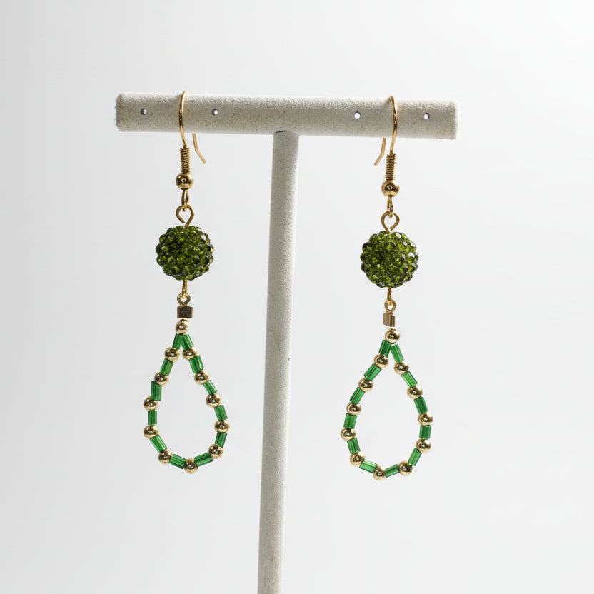 Green beaded earrings on a white stand against a white background
